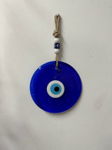 Blue glass evil eye wall hanging measuring 18 cm shown against a neutral wall as protective home decor