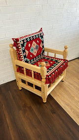 Red square floor cushion set with geometric square cotton cover on a rustic wood chair in a contemporary majlis