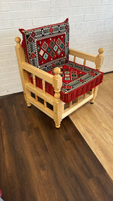 Red floor cushion set with plain warm-red cotton cushion on a rustic wood chair in a relaxed majlis corner