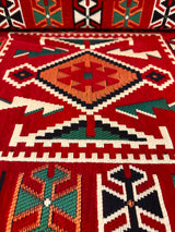 Detail of red rhombus floor cushion showing woven diamond motif and firm sponge edge on red cotton cover