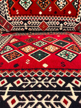 Close cotton-weave detail of red floor cushion showing firm sponge fill and stitched seam on warm red cover