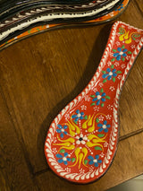 Detail of the deep red glazed ceramic spoon holder revealing hand-painted brush strokes and sheen